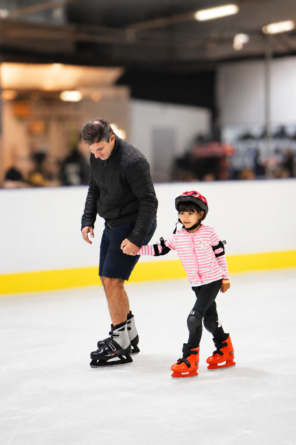 Pai ensinando a filha a patinar no gelo